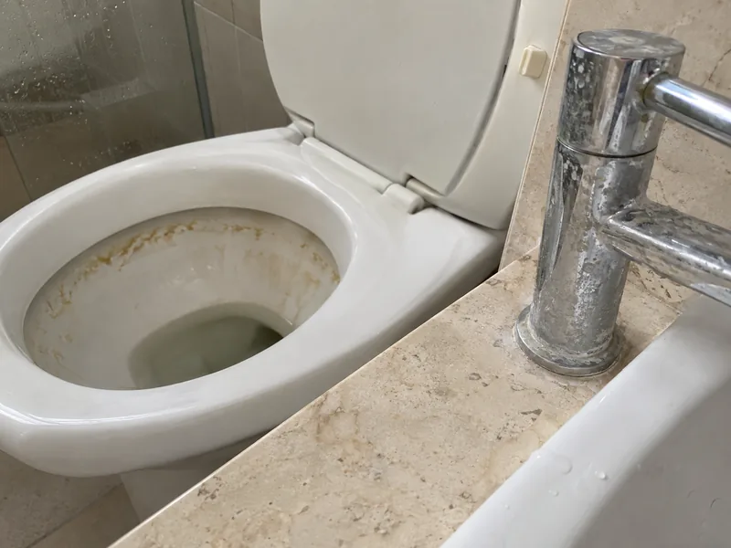Vaso com mancha amarelada e torneira cromada com marcas de calcário
